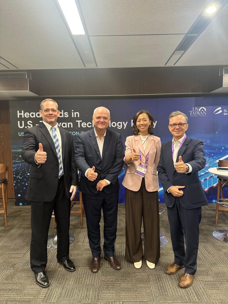 The panelists at the event, standing in front of the event banner with ”thumbs up” gestures. From left: Dan Nystedt, Vice President of Research, TriOrient Investments Ltd. Stephen Braim, Vice President, IBM Heidi Mah, Director, BowerGroupAsia Rupert Hammond-Chambers, President, US-Taiwan Business Council